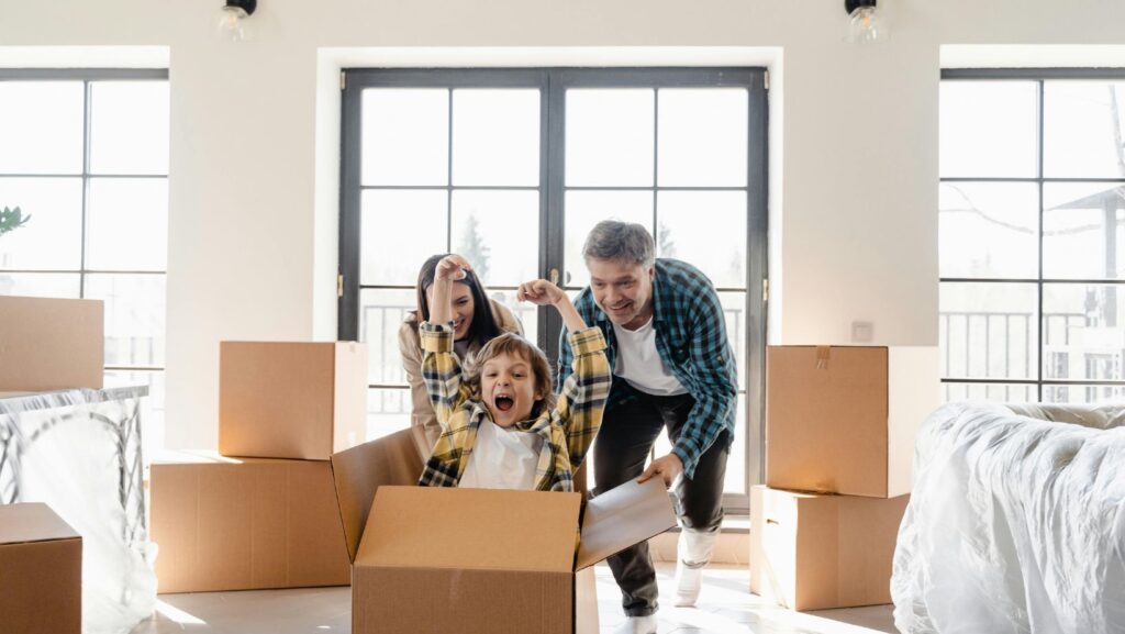 A family having fun with moving boxes in a new home, showing excitement and joy during the relocation